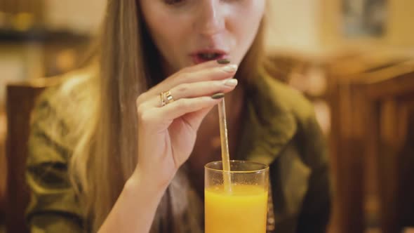 Happy Girl Tasting the Mango Juice and Smiling in Cafe