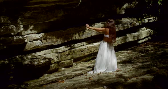 Alluring Female Belly Dancer Is Moving in Forest on Rocks, Back View