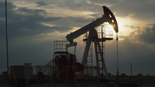 Oil Mining, an Oil Rig in the Field Pumps Out Oil, View of an Oil Rig at Sunset, Resource Extraction