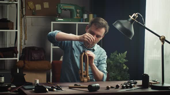 Man Tailor Sewing Two Pieces of Leather on Stand Using Professional Sharp Needle and Strong Thread
