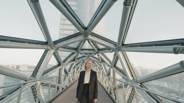 Confident Business Woman Walking Along Long Glass Bridge