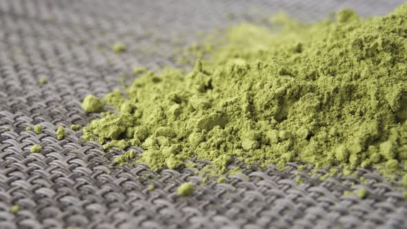 Unfiltered matcha green tea powder close-up on textured gray mat