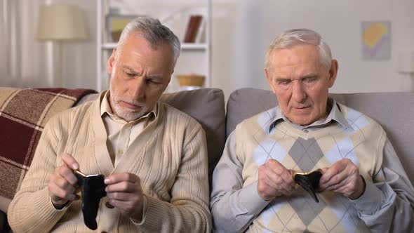 Unhappy Senior Men Sitting on Sofa, Looking in Empty Wallet, Social Insecurity