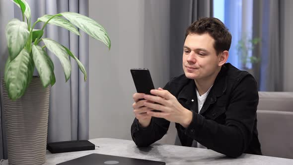 Young Man Holding Smart Phone Arrange Delivery and Resting at Studio Apartment