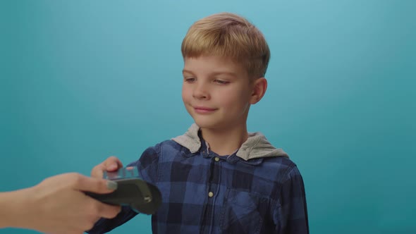 Blonde boy paying with credit card and contactless NFC terminal