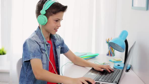 Boy in Headphones Playing Video Game on Laptop