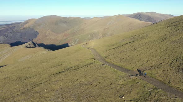 Aerial view of people hiking and climbing Snowdon mount in Wales on a sunny d