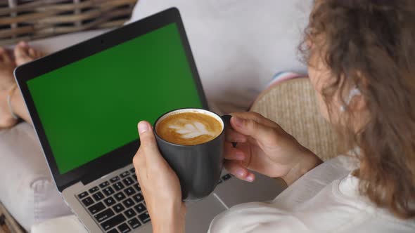 Top View of Female Sitting with Mug of Cappuccino Working on Her Laptop
