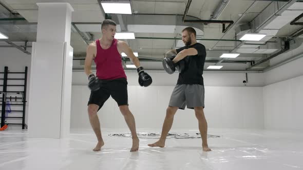 The Coach and the Fighter Work Out the Kick in the Jump Knee on the Paws in Slow Motion