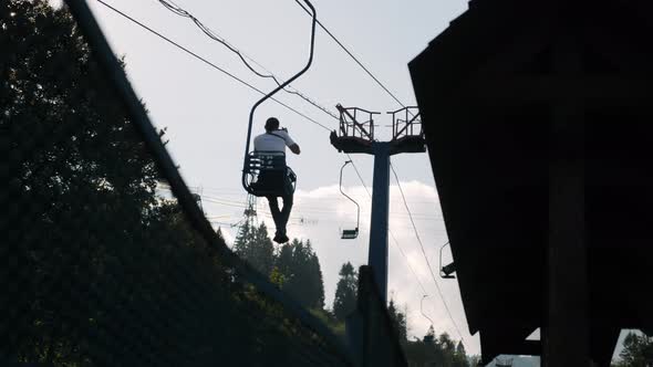 Active tourist is riding chairlift through the mountainside