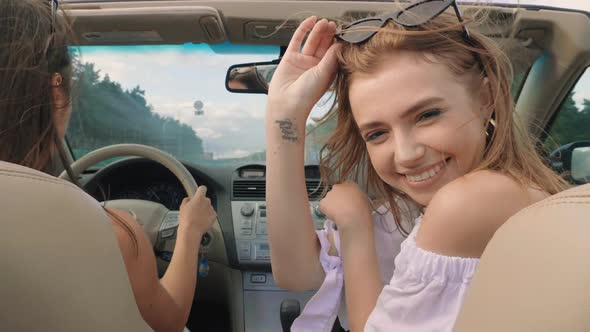 Portrait of two young beautiful and smiling hipster girls in convertible car