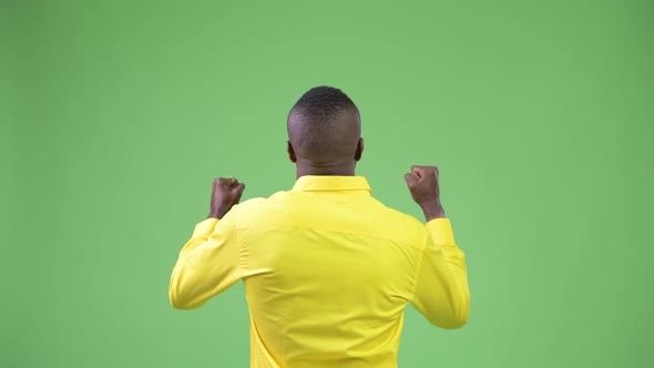Rear View of Young African Businessman Wearing Yellow Shirt Looking Excited