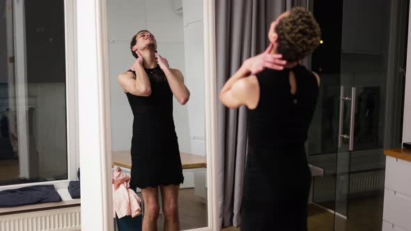 A Man in Little Black Dress in Front the Mirror Sensually Moves