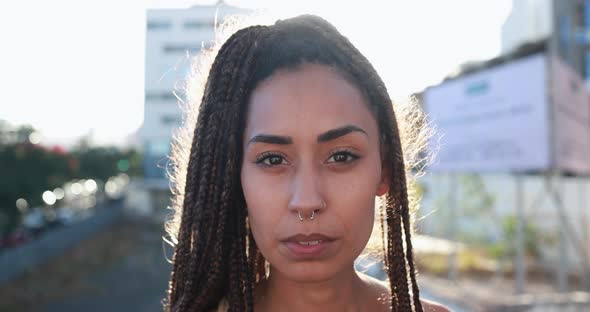 Bohemian mixed race girl looking serious on camera with city and sunset in the background