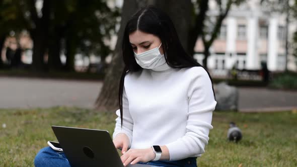 Girl in a Protective Mask Works on a Laptop