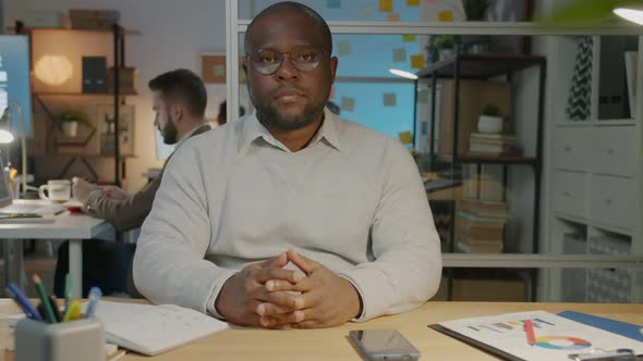 Slow Motion Portrait of Serious Man Manager Sitting at Desk in Dark Office Room