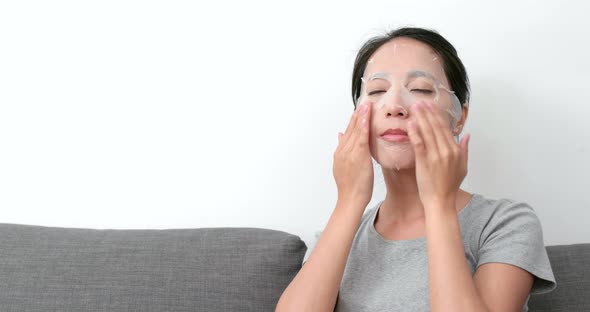 Woman apply paper mask sheet on face 