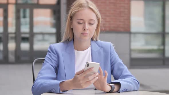 Young Businesswoman Using Smartphone Sitting Outdoor