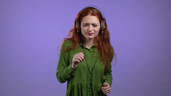 Pretty Woman with Headphones on Purple Studio Background