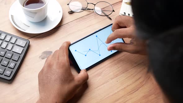 Man's Hand Analyzing Stock Chart on Smart Phone