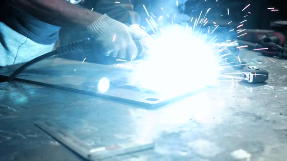 Welder at Work. Worker Welds Metal Parts. Welding Process, Sparks, Flame, Smoke.