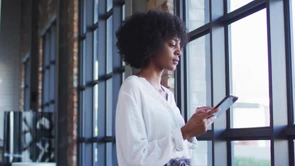 Happy african american woman standing in cafe using digital tablet and smiling