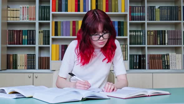 Teenage Girl Student with Glasses Studying in the School Library