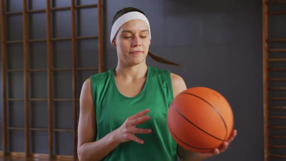 Portrait of caucasian female basketball player holding ball