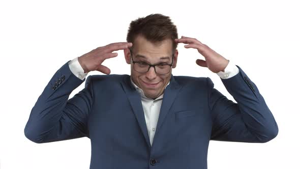 Young Ambitious Businessman in Blue Suit and Glasses React to Something Riddiculous Showing Head