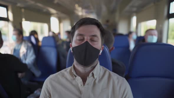 Male in Headphones Falling Asleep on the Train Wearing Facemask During Coronavirus Pandemic