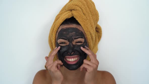 Young smiling woman applying facial charcoal mask portrait