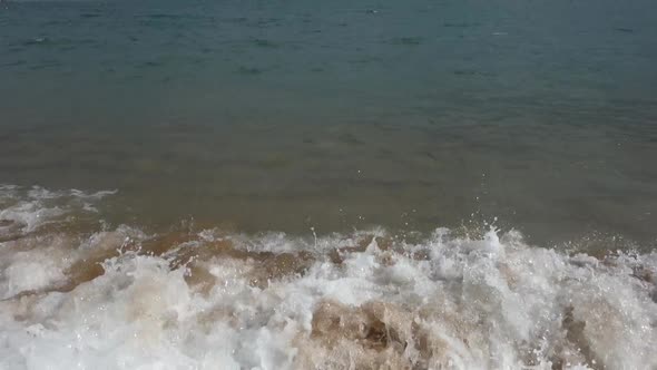 waves crashing on beach sand, slow motion