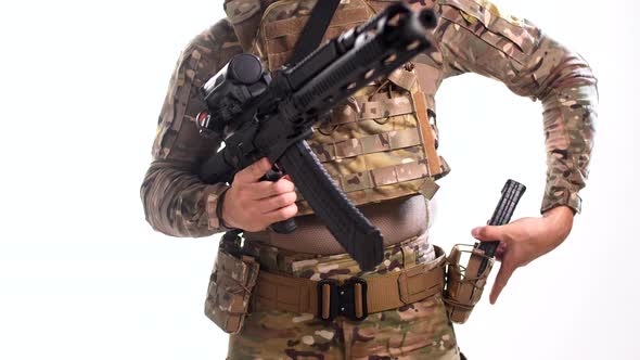 Man in combat camouflage and body armor disengages the safety on his rifle