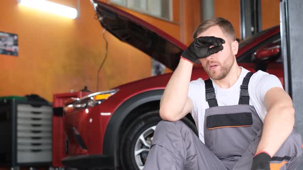 Tired Male Car Mechanic During Lunch Break