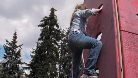 Blonde Junior Schoolgirl with Plait Climbs Up Wooden Wall