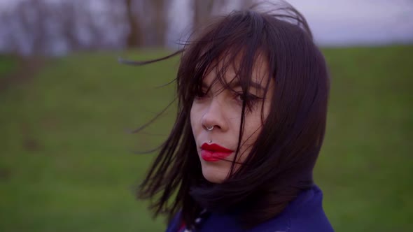 Portrait of a Dark-haired Young Pretty Girl Walking on the Street on the Grass, She Has Bright