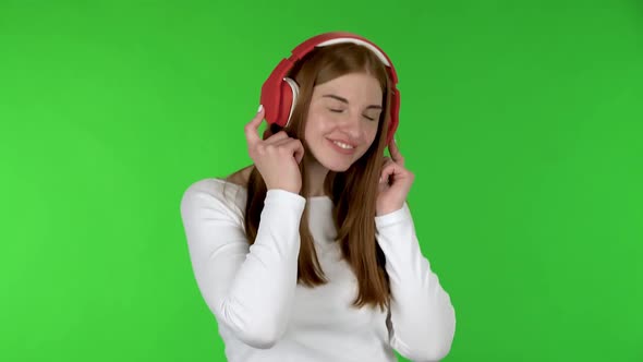 Portrait of Pretty Young Woman Is Dancing and Enjoying Music in Big Red Headphones.