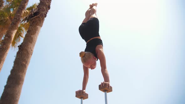 A Young Blonde Woman Doing a Handstand on the High Small Beams