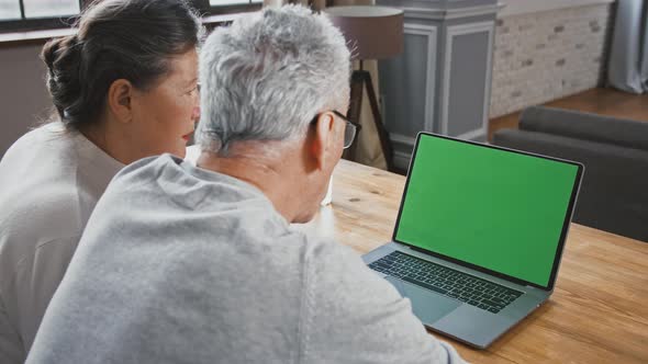 Back View of Aged Couple Looking at Green Screen of Laptop and Talking to Someone Using Online Video