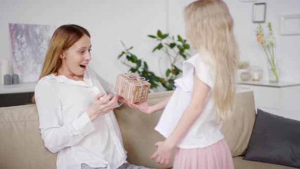 Cute Blond Girl Giving Present to Mother on Mothers Day