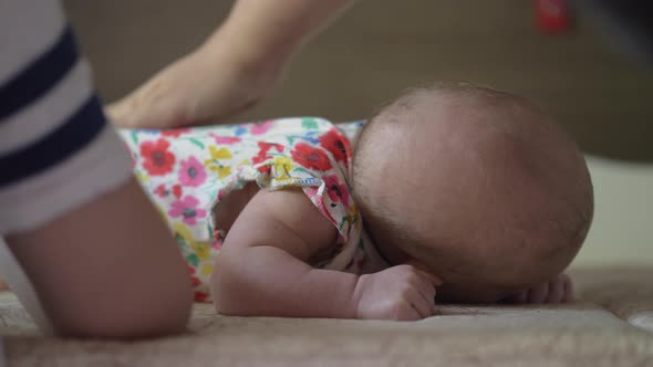 Mother and elder child looking after baby at home