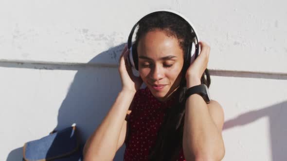 African american woman wearing headphones and listening to music on promenade by the sea