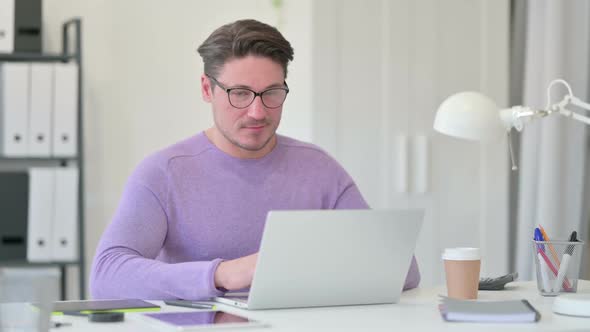 Middle Aged Man with Laptop Smiling at the Camera