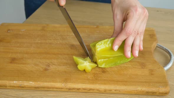 Female Hands are Holding Knife and Cutting Exotic Ripe Starfruit or Averrhoa Carambola