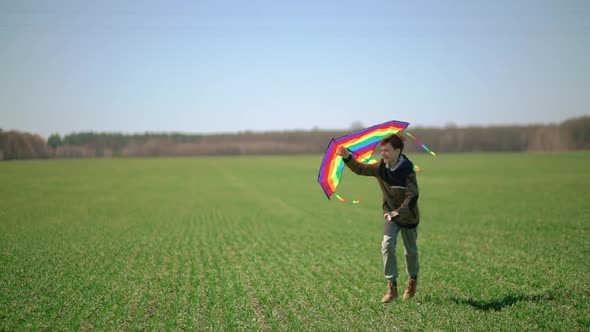 A Boy Runs Across a Green Field with a Kite