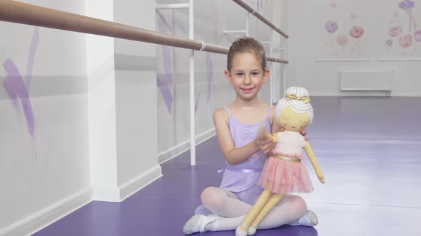 Full Length Shot of a Lovely Little Ballerina Waving To the Camera Playing with a Doll