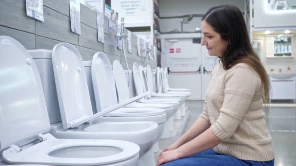Young Woman Chooses Toilet Bowl with Seat Lift