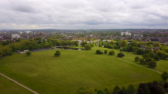 Flying over a London Common towards a duck pond and houses in the background