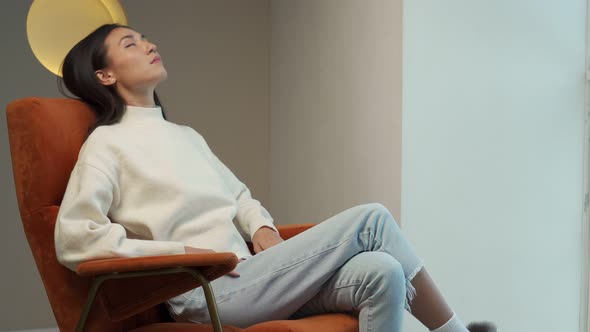 Smiling Asian Woman Resting in a Comfortable Chair Happy After the Work Done Enjoying the Rest with