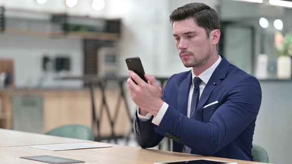 Serious Businessman Using Smartphone in Office 